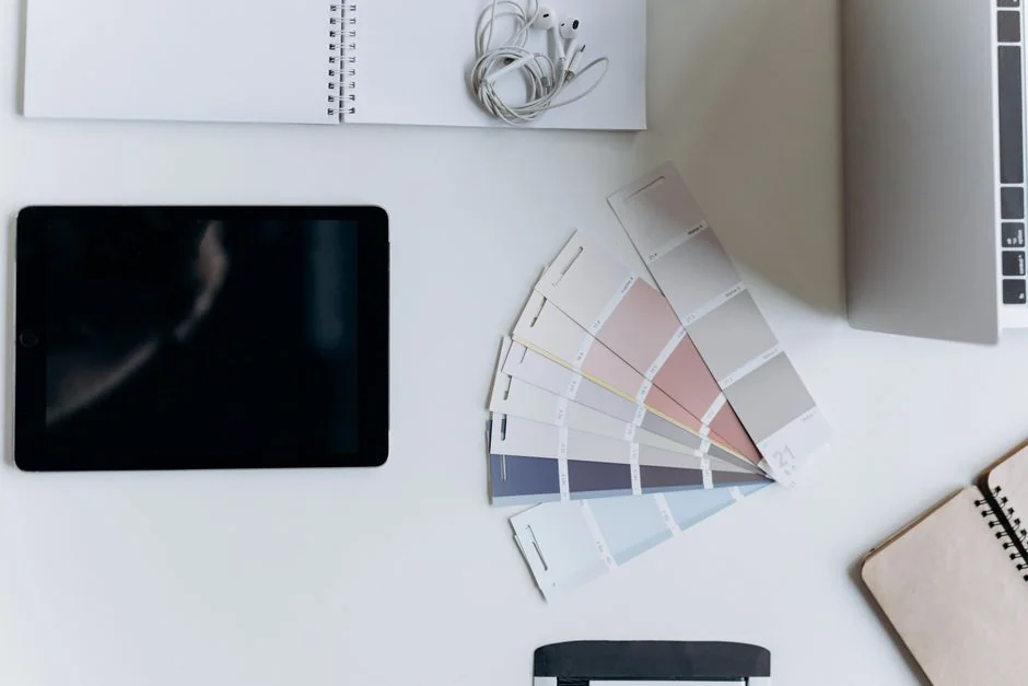 Close-up of colorful design sketches in a spiral notebook with color swatches on a white desk.